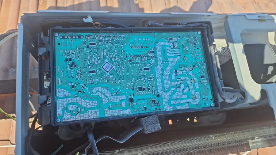 Close-up of the electronic control board inside an outdoor AC unit